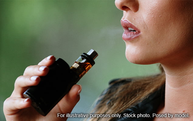 Woman holding vape with brown e-liquid